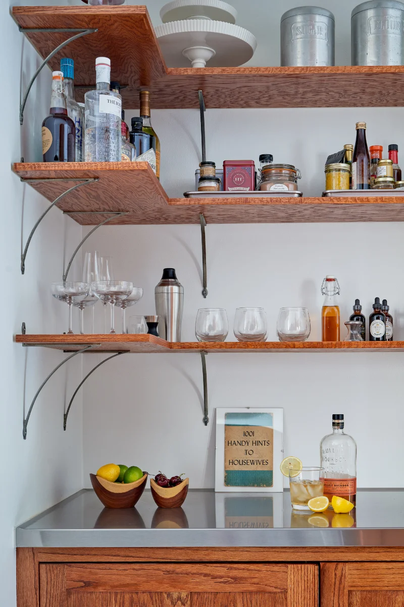 A corner of Wende Bungalow features a well-stocked bar with wood shelves and a stainless steel countertop.
