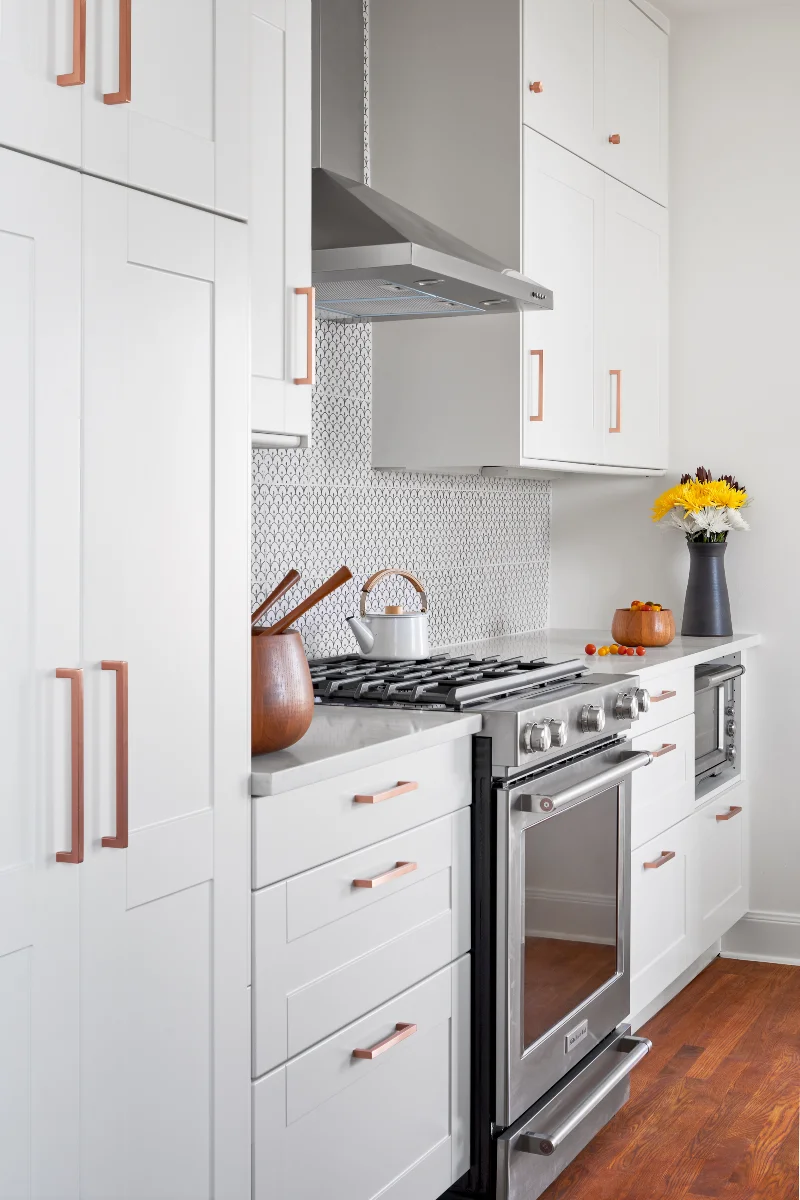The Queen Anne House kitchen features white wall-to-ceiling cabinetry and stainless steel appliances.