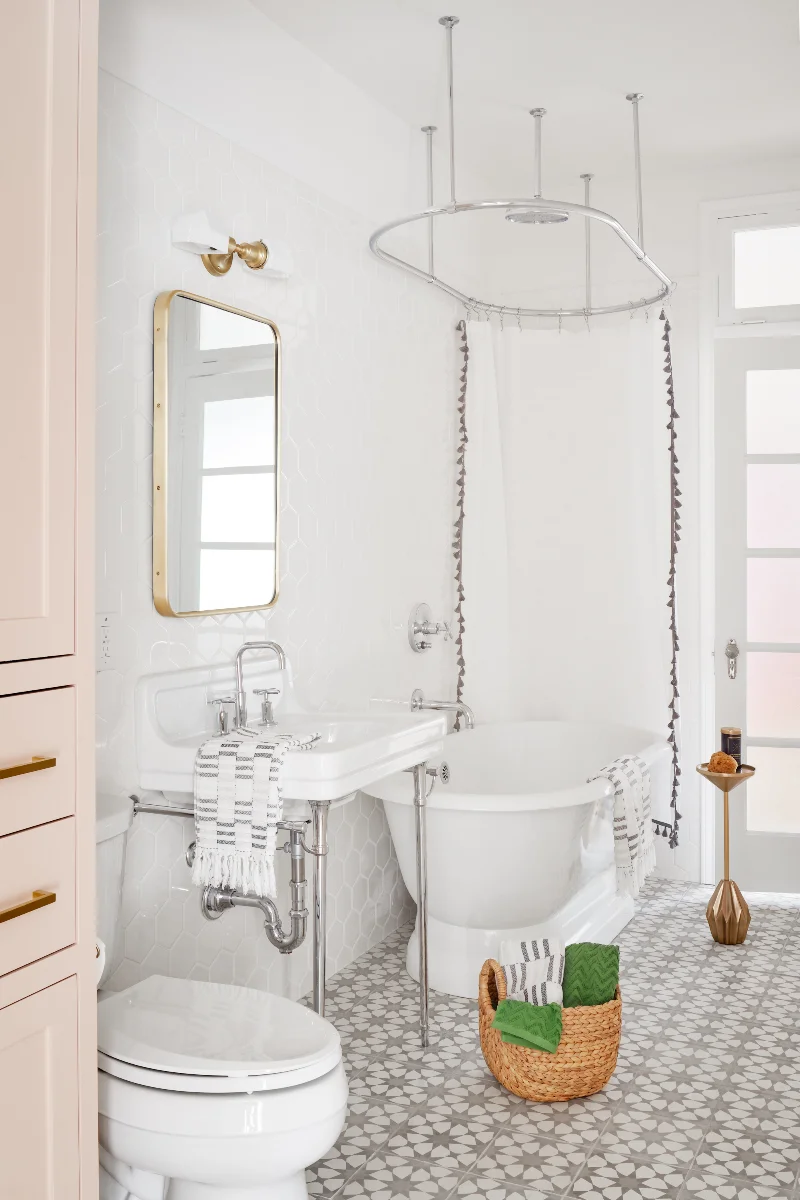 An inviting bathroom space in the Queen Anne House features a pedestal bathtub, clean white fixtures, and a star-patterned tile floor.