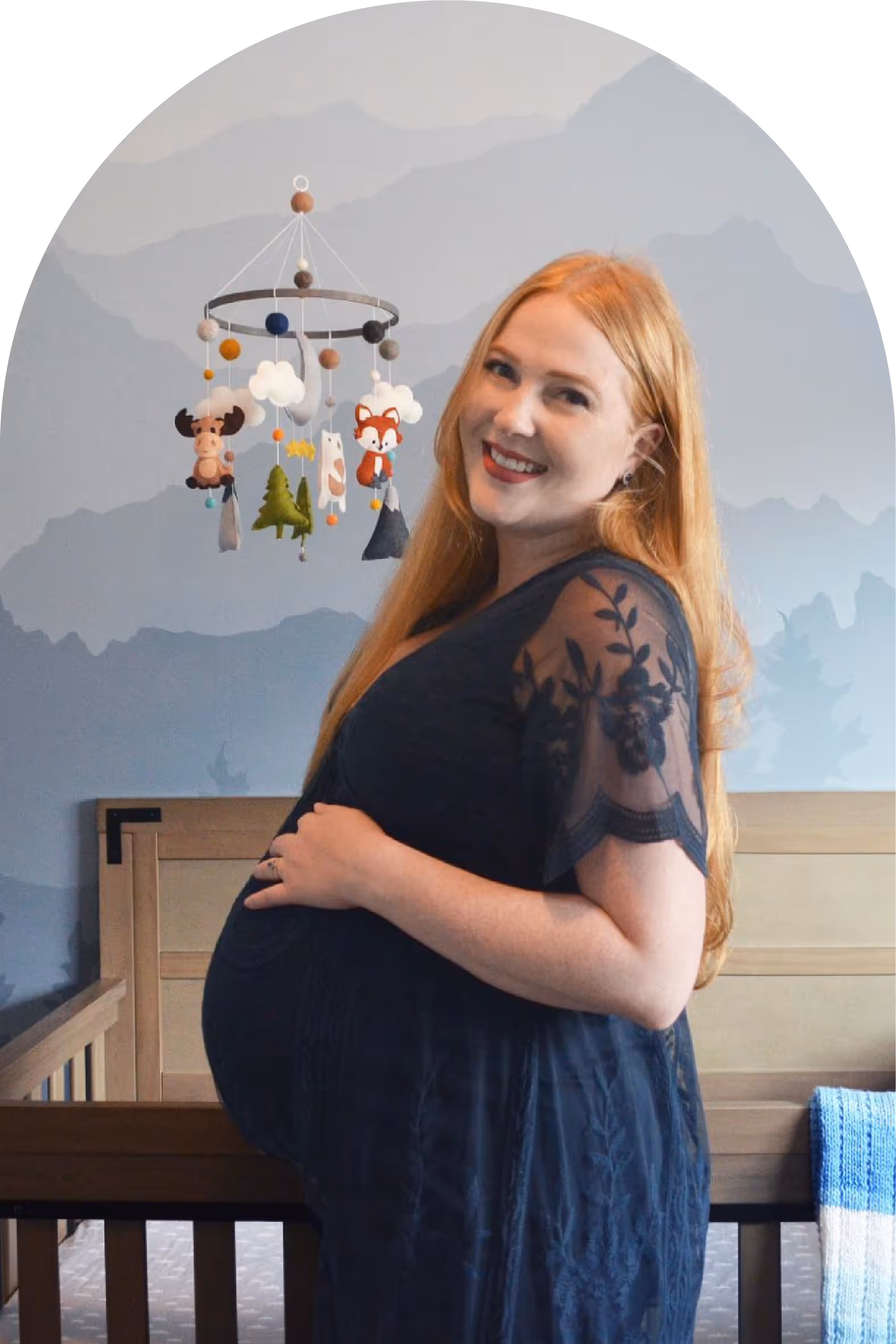 Portrait of Kasia Flood standing in front of a mountain mural she painted with new nursery