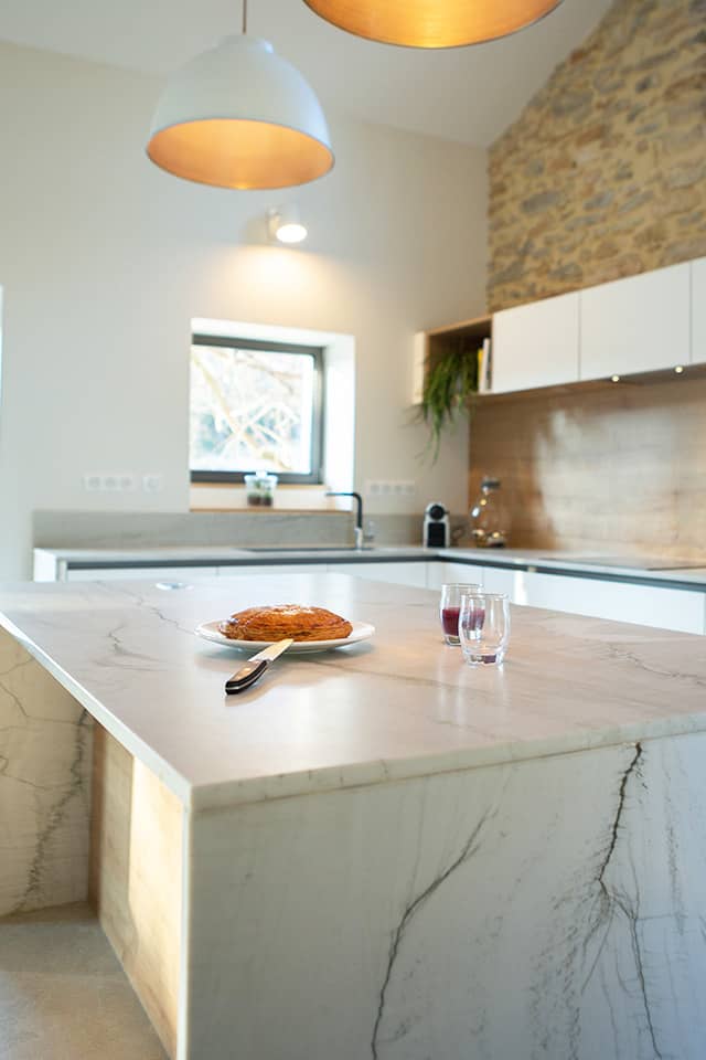 Projet de l'Atelier de Léa : focus sur le plan de travail en marbre d'une cuisine contemporaine minimaliste blanche sur-mesure.