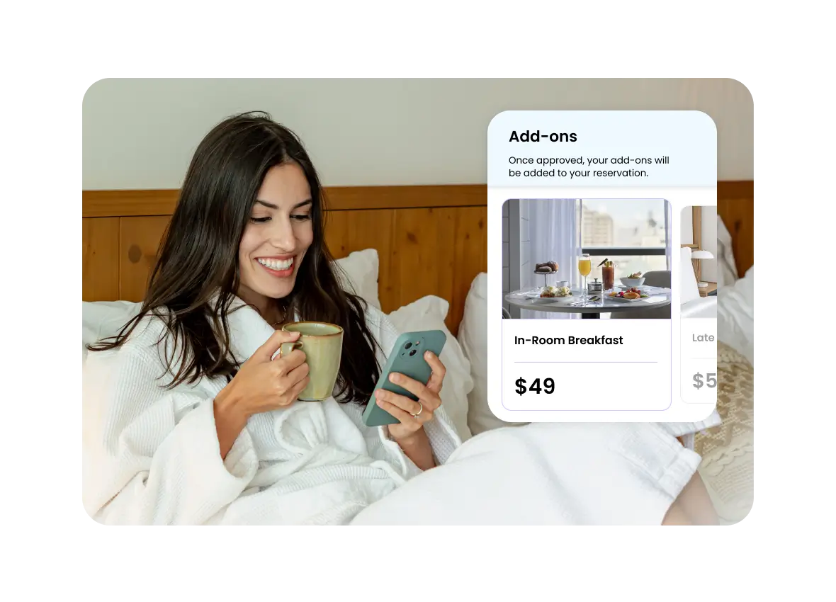 Woman in bathrobe sitting on bed, holding a cup and looking at her smartphone with a hotel add-ons menu showing In-Room Breakfast for $49.