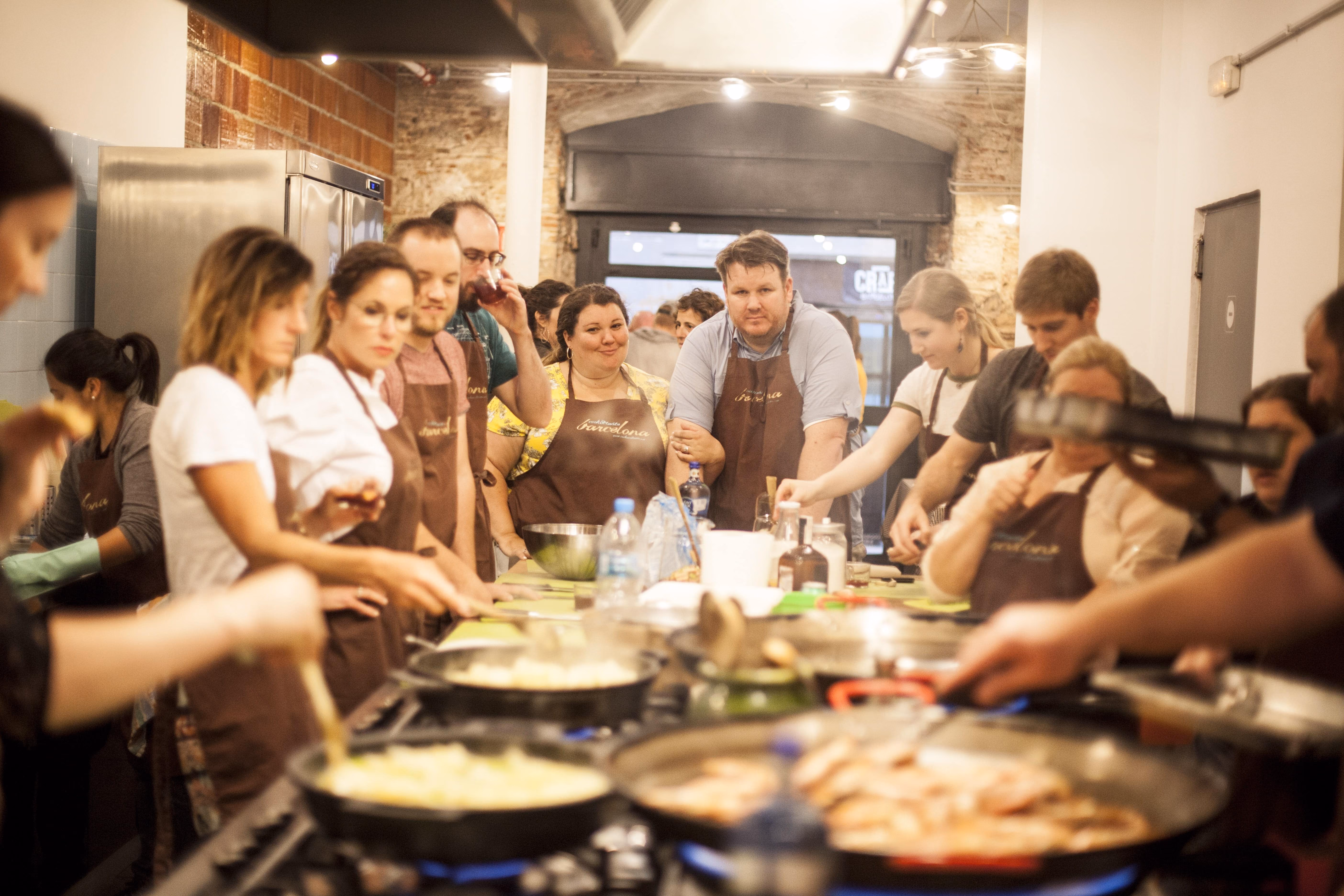 Cooking class with multiple participants preparing food in commercial kitchen