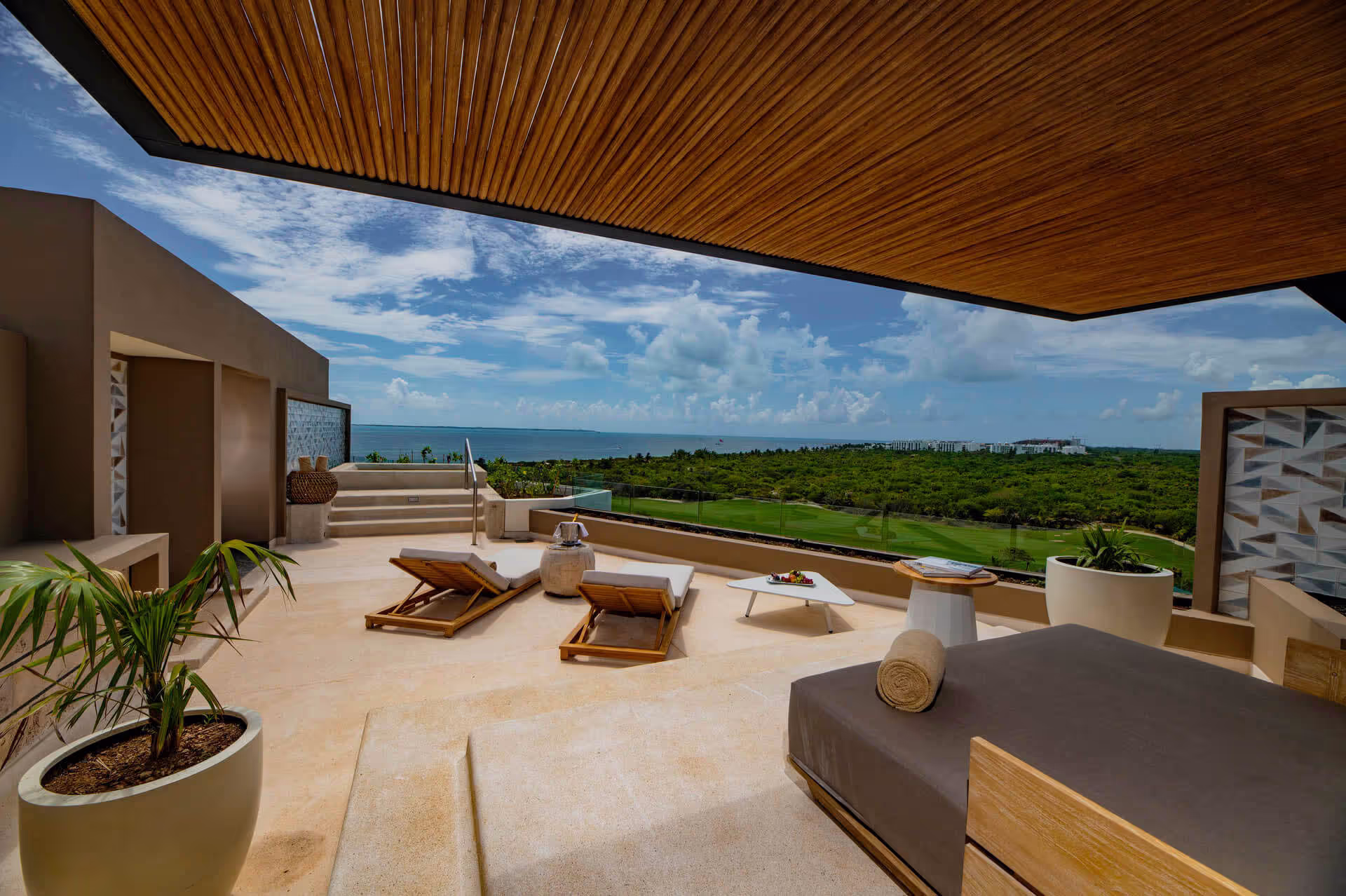 Luxury terrace with ocean view, lounge chairs, and tropical landscape