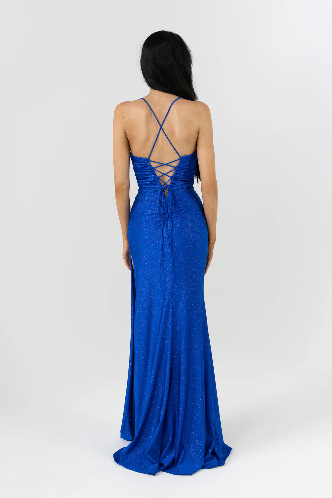 Make a statement in our glamorous Vega formal dress by Tania Olsen Designs, crafted from a soft sparkle knit that hugs your curves in a flattering fitted silhouette. The bodice features a softly draped sash detail that adds texture and elegance, while the V-neckline and delicate spaghetti straps that lace up at the back create a romantic, adjustable fit.