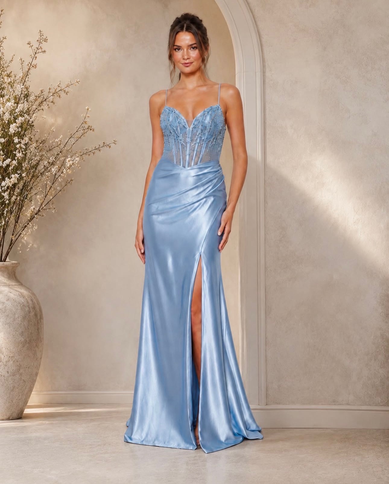 The Carmella Formal Dress is a fitted, full-length gown crafted from stretch satin for a sleek, contoured silhouette. The skirt features a thigh-high split and ruching from one hip, adding movement and flattering definition.