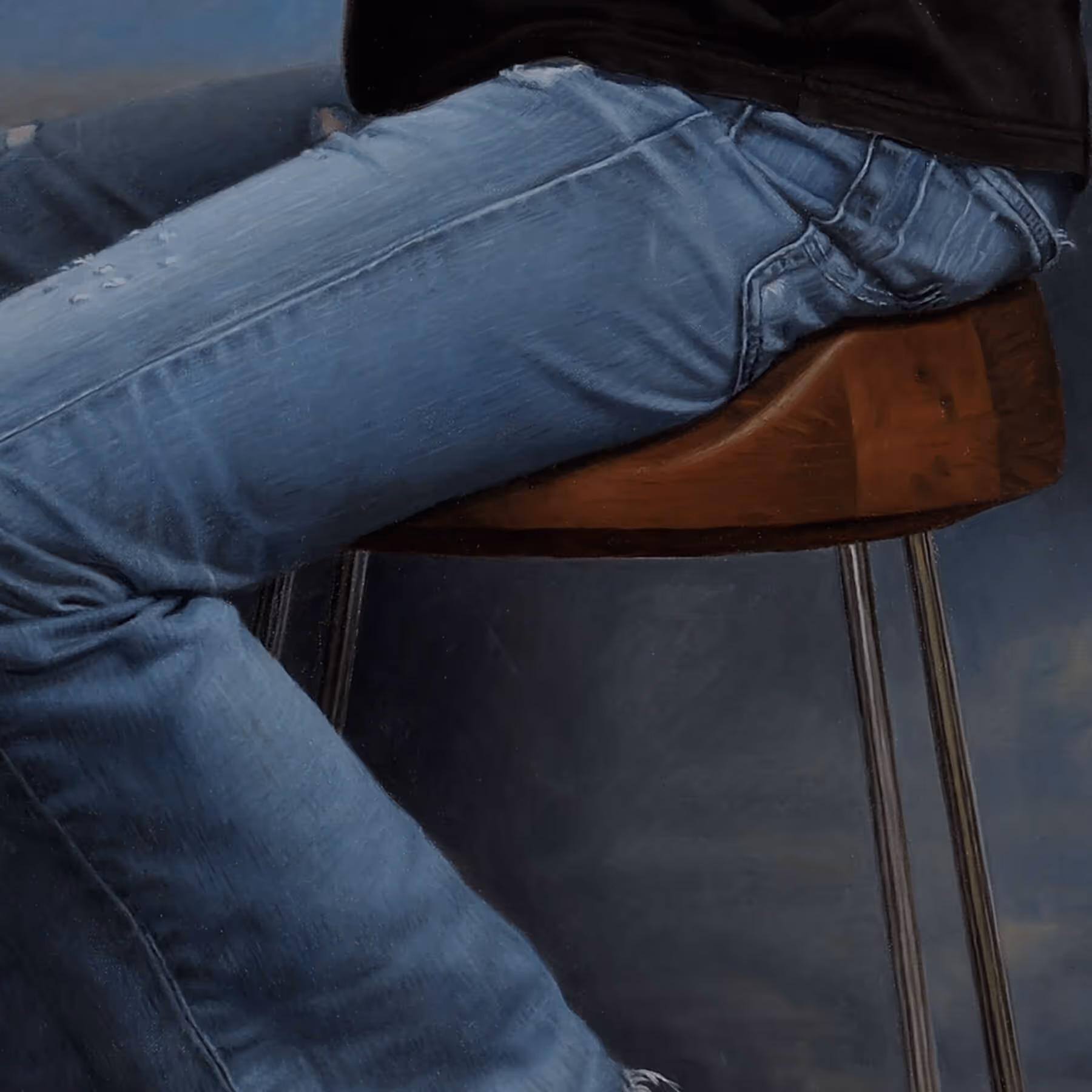 Detail of Patrick’s seated pose, jeans, and contemporary stool in a portrait by Marvin Mattelson.