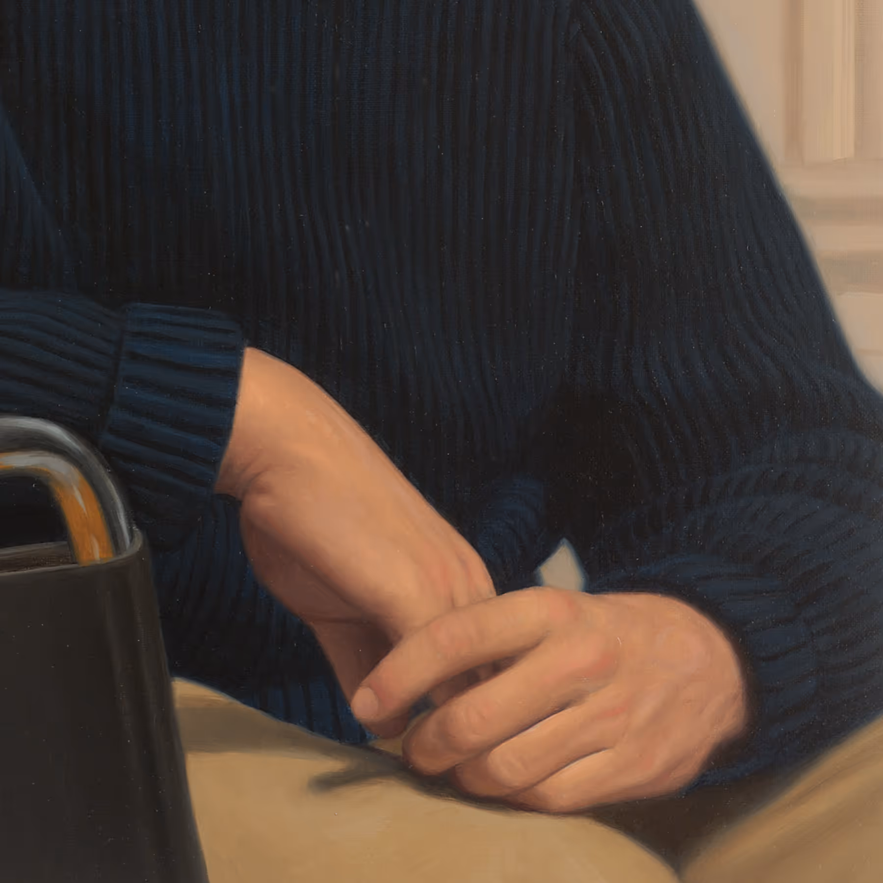 Detail of Eric’s hands, dark blue sweater, and contemporary portrait composition.