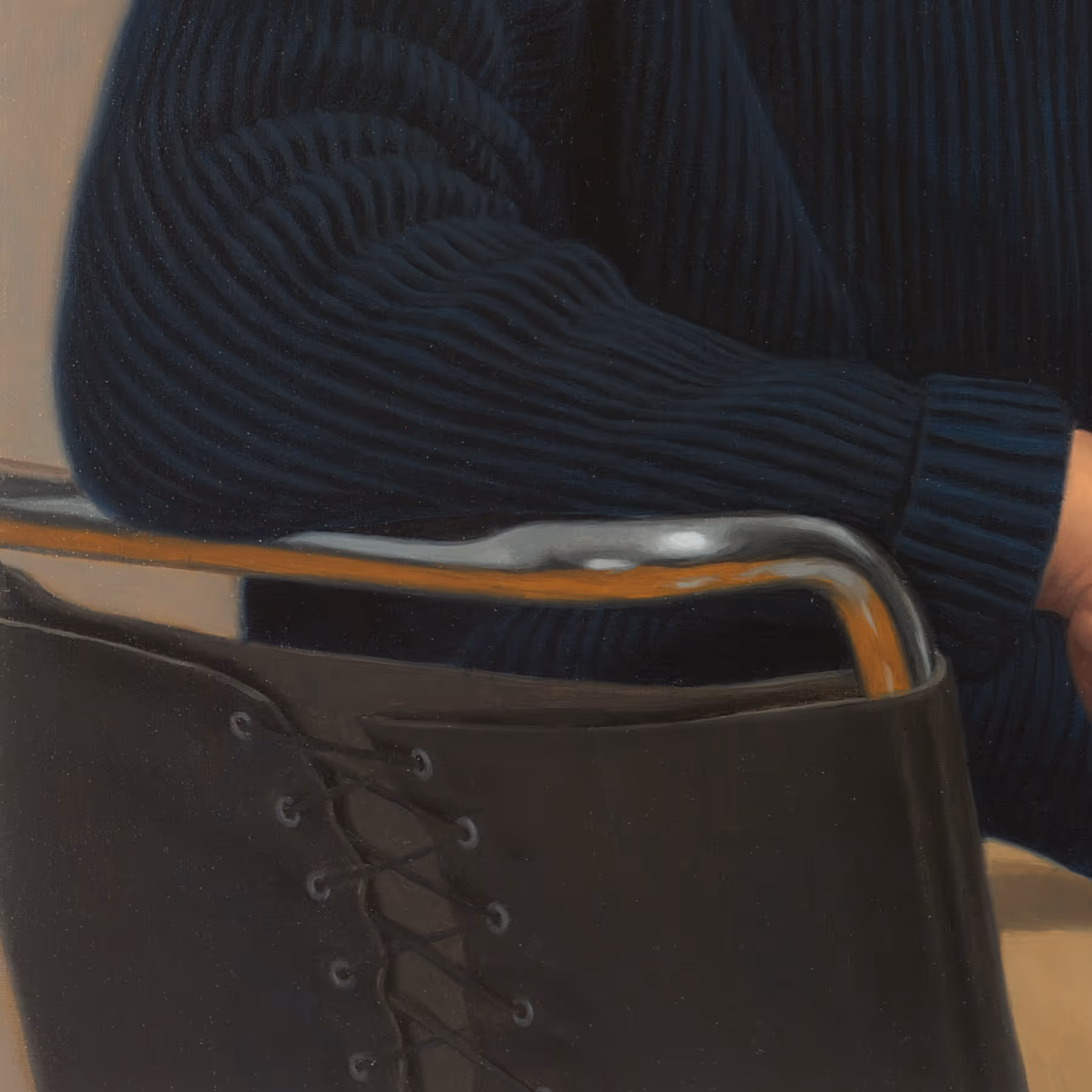 Detail of the modern chair and dark blue sweater showing abstract shapes and reflective surfaces.
