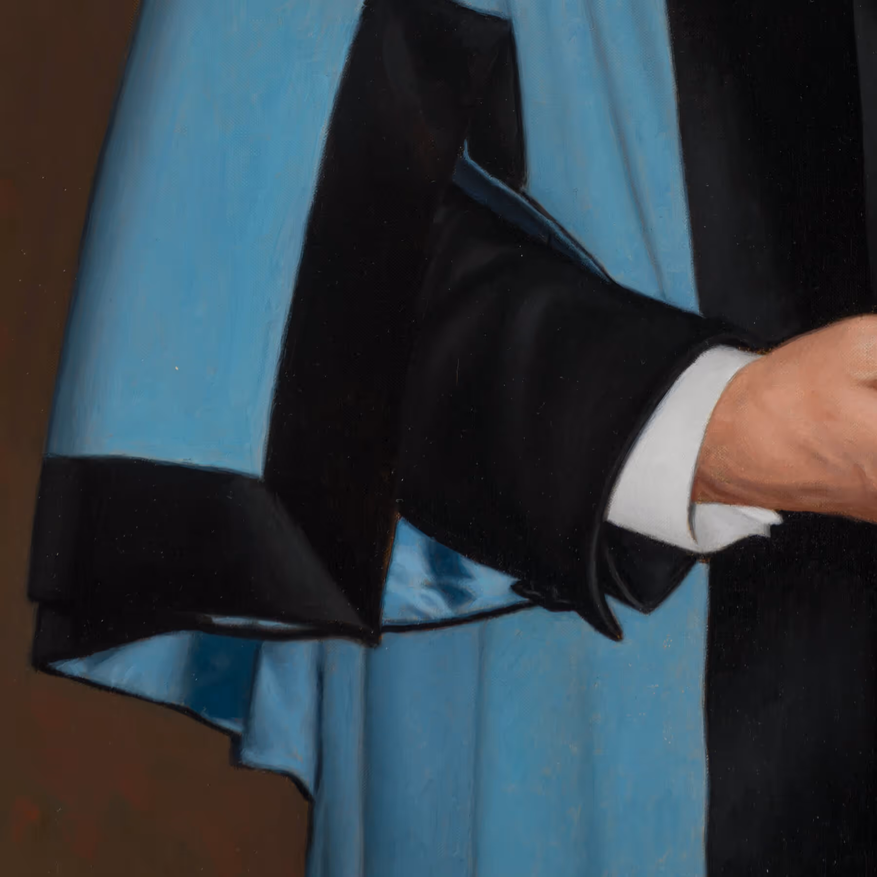 Detail of Edward Cripps’s academic gown showing blue fabric, satin trim, and draped sleeve.