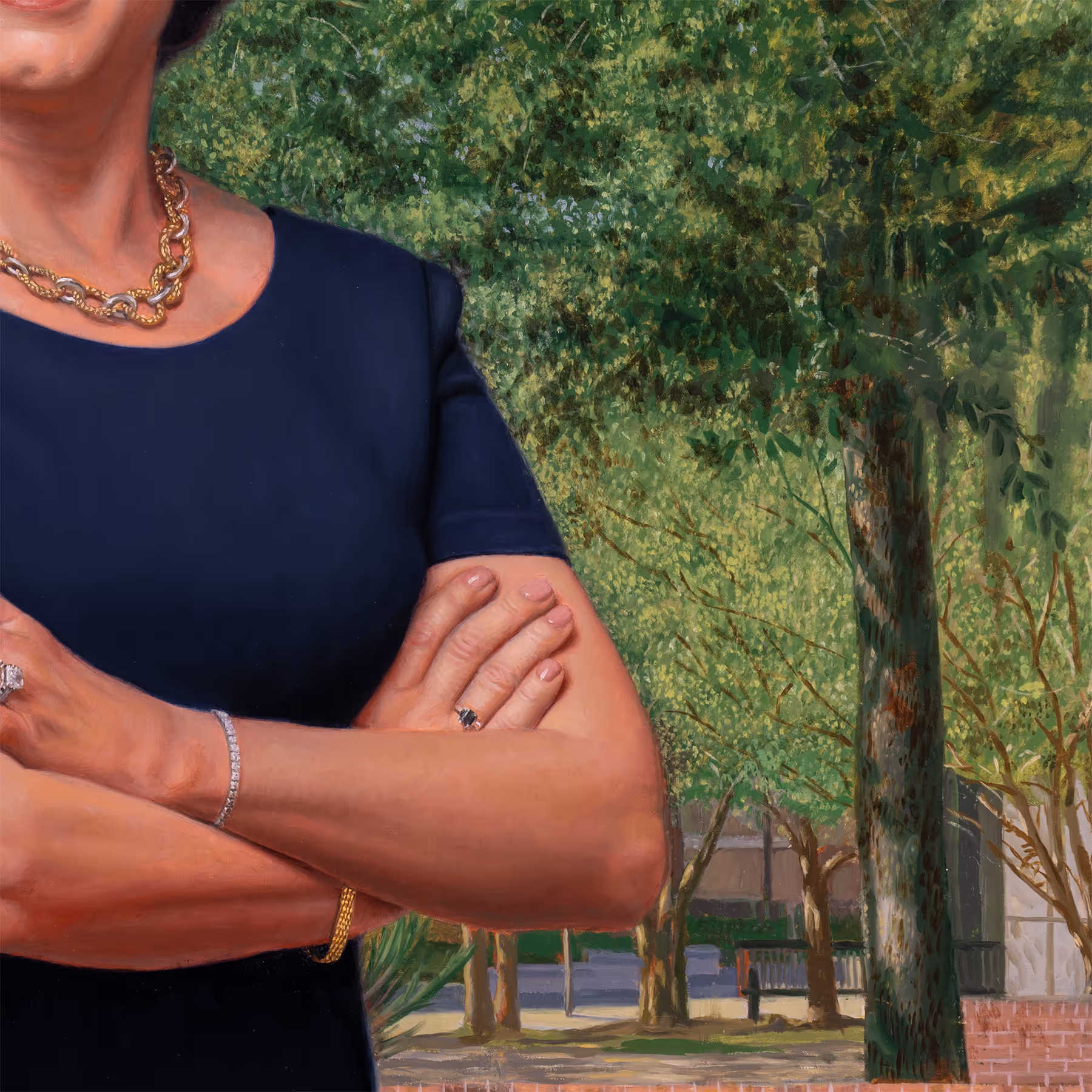 Detail of Julie Johnson with folded arms beside a slender tree trunk.