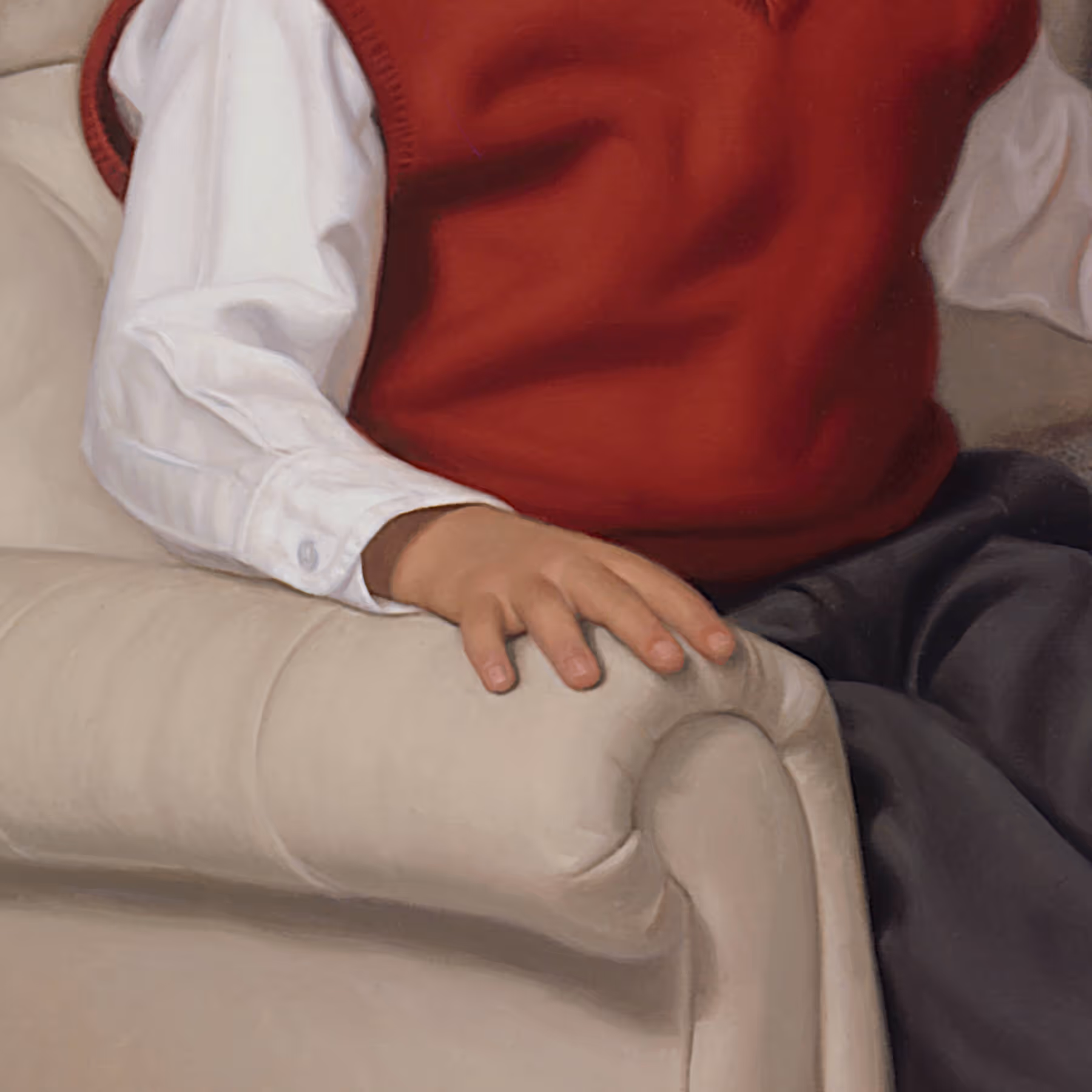 Detail of Andrew’s hand, red sweater vest, and tailored clothing against a light beige chair.