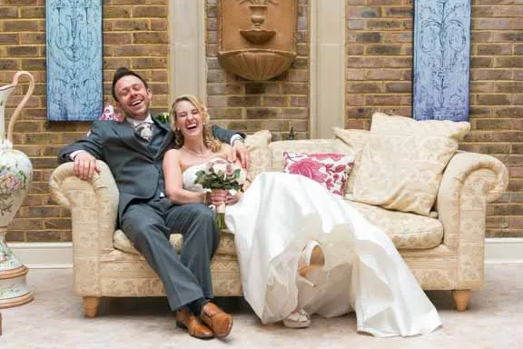 Bride & groom sat on sofa laughing at De Courceys Manor Cardiff