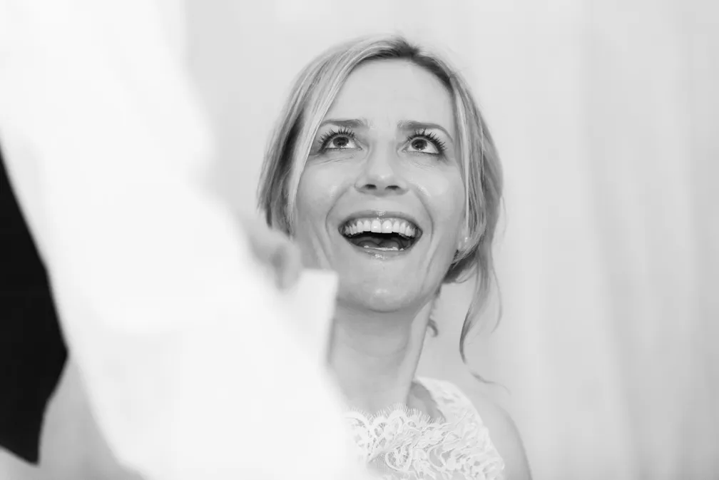Smiling woman looking upward with joyful expression, wearing a lace dress.