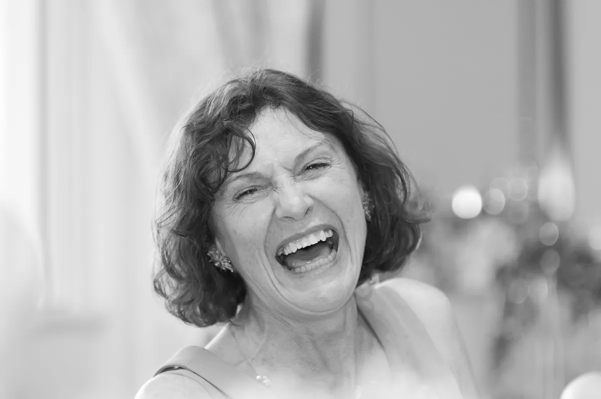 Black and white close-up of a woman with short curly hair laughing joyfully.