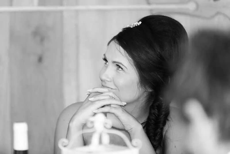 Black and white portrait of a woman with dark braided hair looking up and smiling thoughtfully.