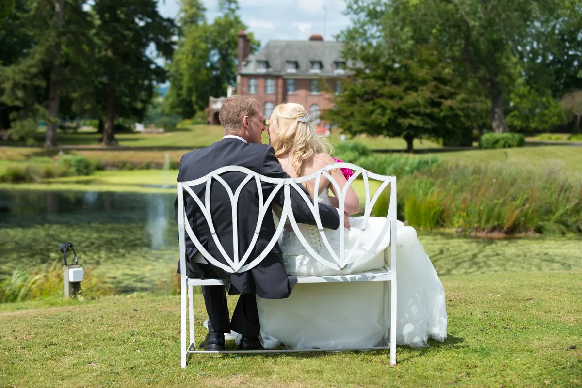 Bride and groom sat on bench in the gardens of Sant Ffraed House, Abergavenny