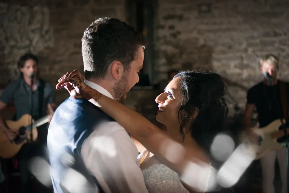 Bride and groom dancing closely at wedding reception with a live band playing in the background.