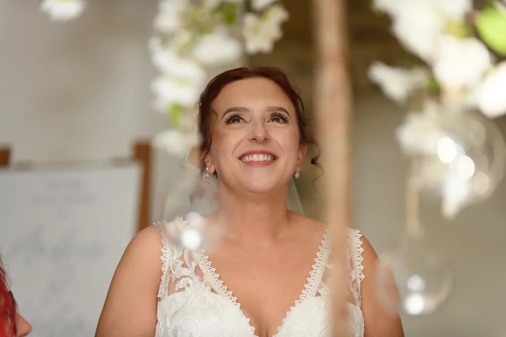 Smiling bride with red hair in a white lace wedding dress looking upwards.