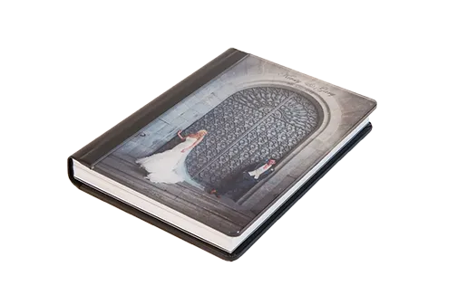 Closed photo album with a wedding photo cover showing bride and groom in front of large ornate iron doors.