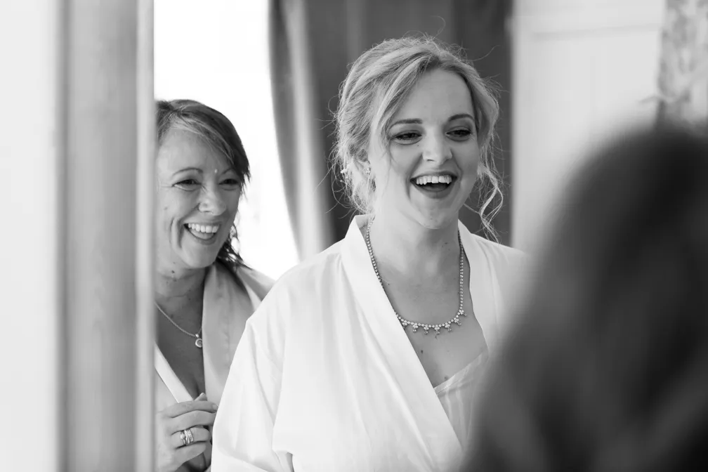 Black and white photo of two smiling women in robes, one wearing a necklace, indoors.