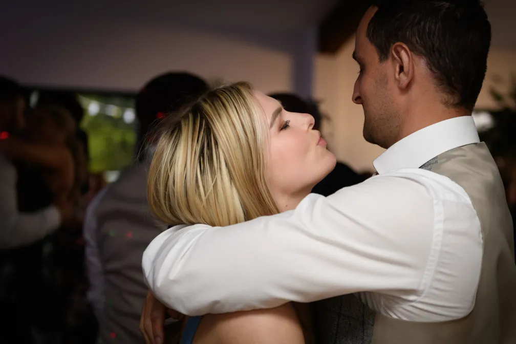 Couple embracing and looking at each other closely in a dimly lit room.