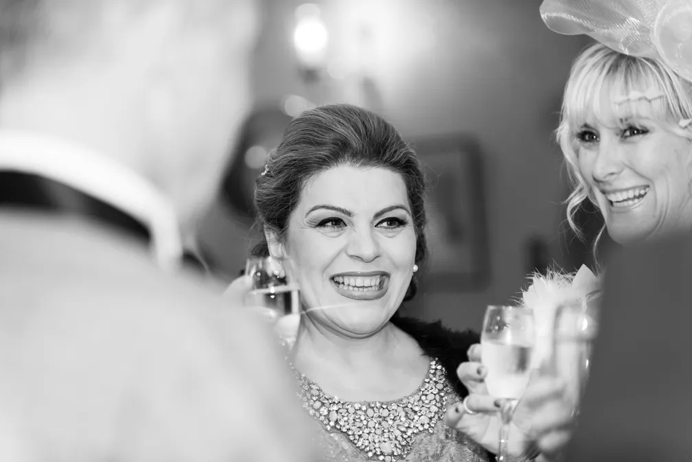 Two women smiling and toasting with champagne glasses at a social event.