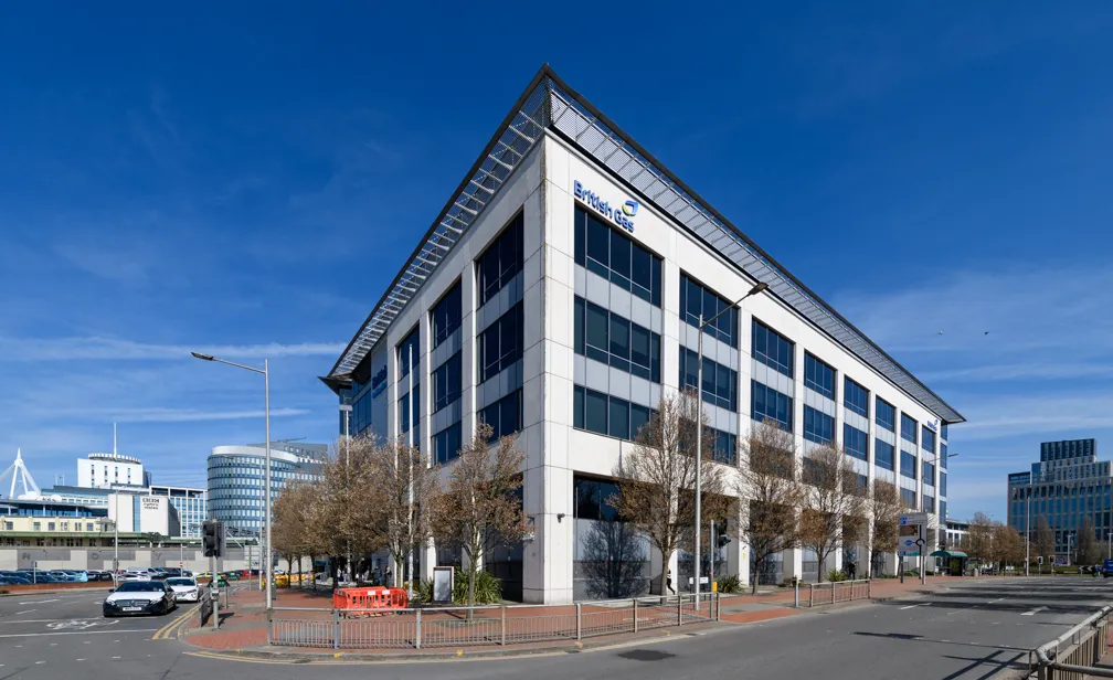 Modern British Gas office building with large windows under a clear blue sky surrounded by trees and street.
