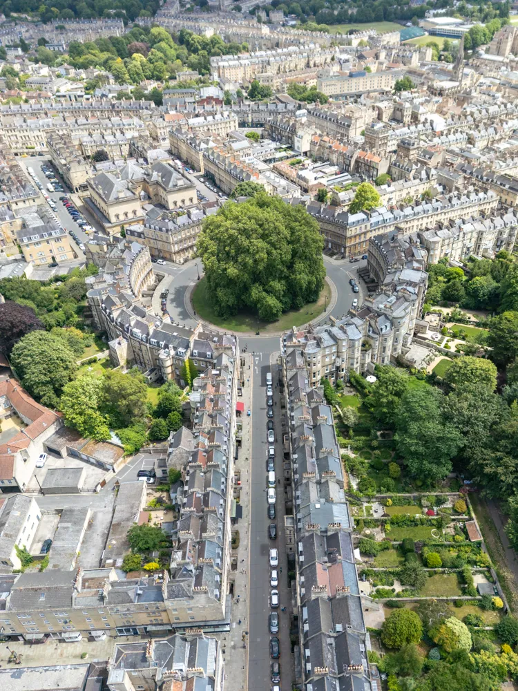 Aerial view of Georgian-style buildings arranged around a circular green space with dense trees in the center.