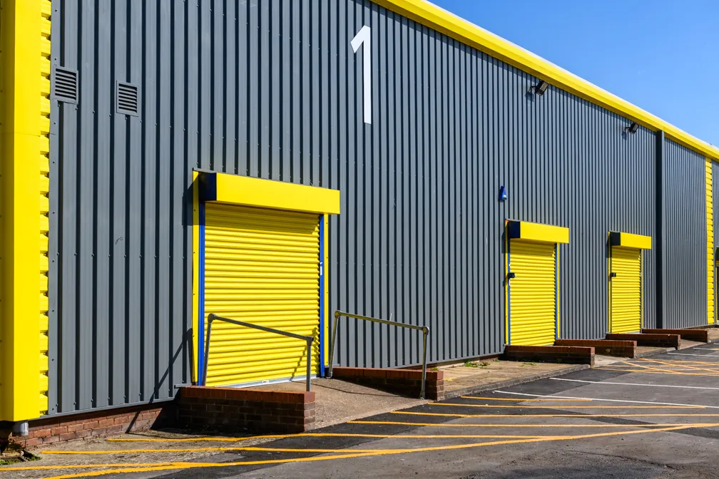 Exterior of a gray industrial building with yellow loading dock doors and a large white number 1 above.