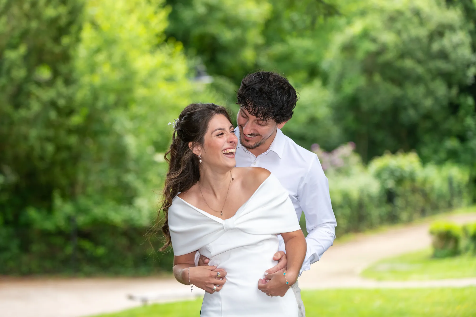 Bride & groom in white laughing in Pontypool Park after a ceremony in Pontypool Registry Office