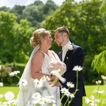 bride & groom in gardens with daisies at a wedding at The Glen Yr Afon Hotel, Usk by Andrew Hazard Photography