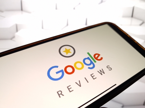 Person writing a detailed Google review on a phone at a restaurant table