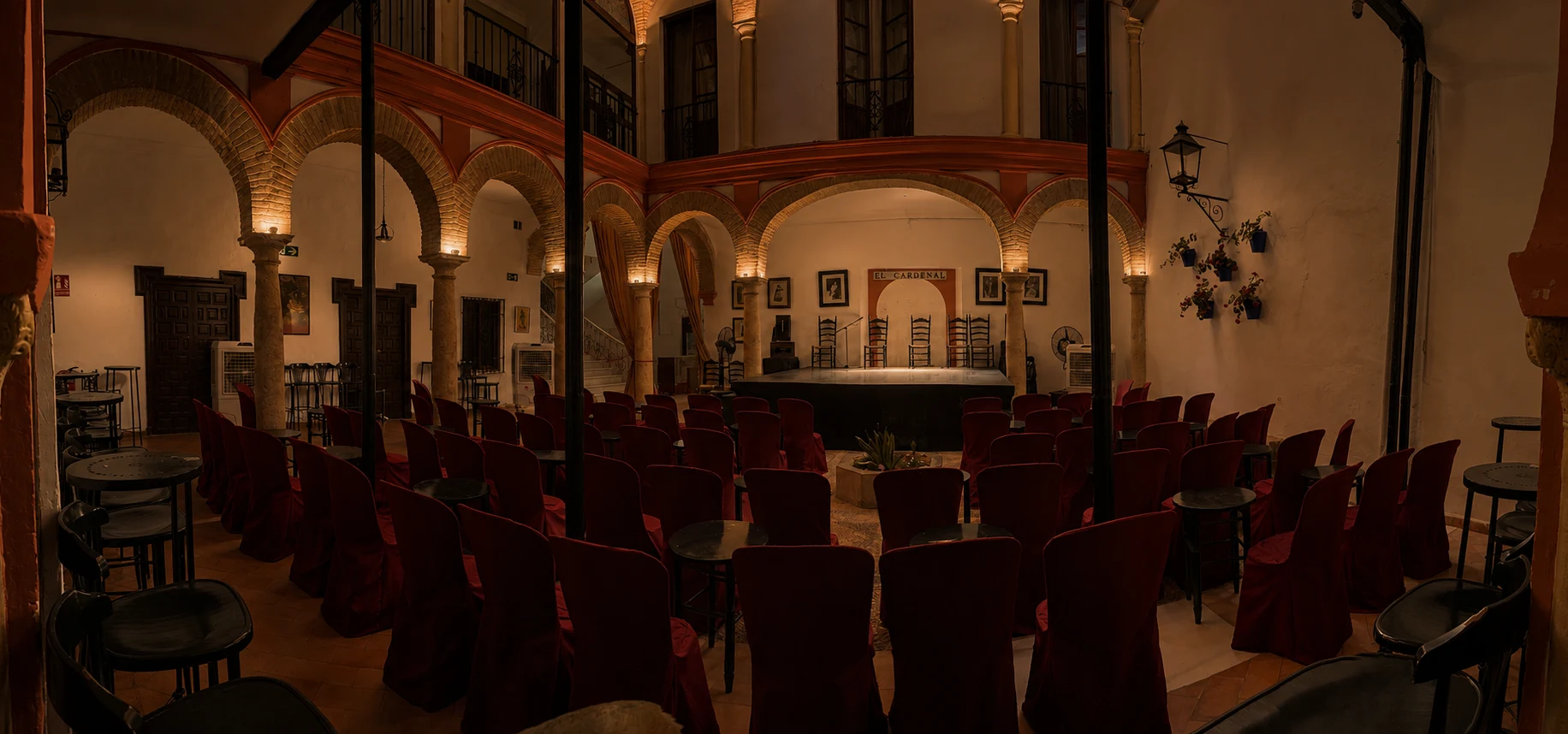 Vista panorámica del patio y escenario de El Cardenal con un tratamiento de iluminación nocturna cálida