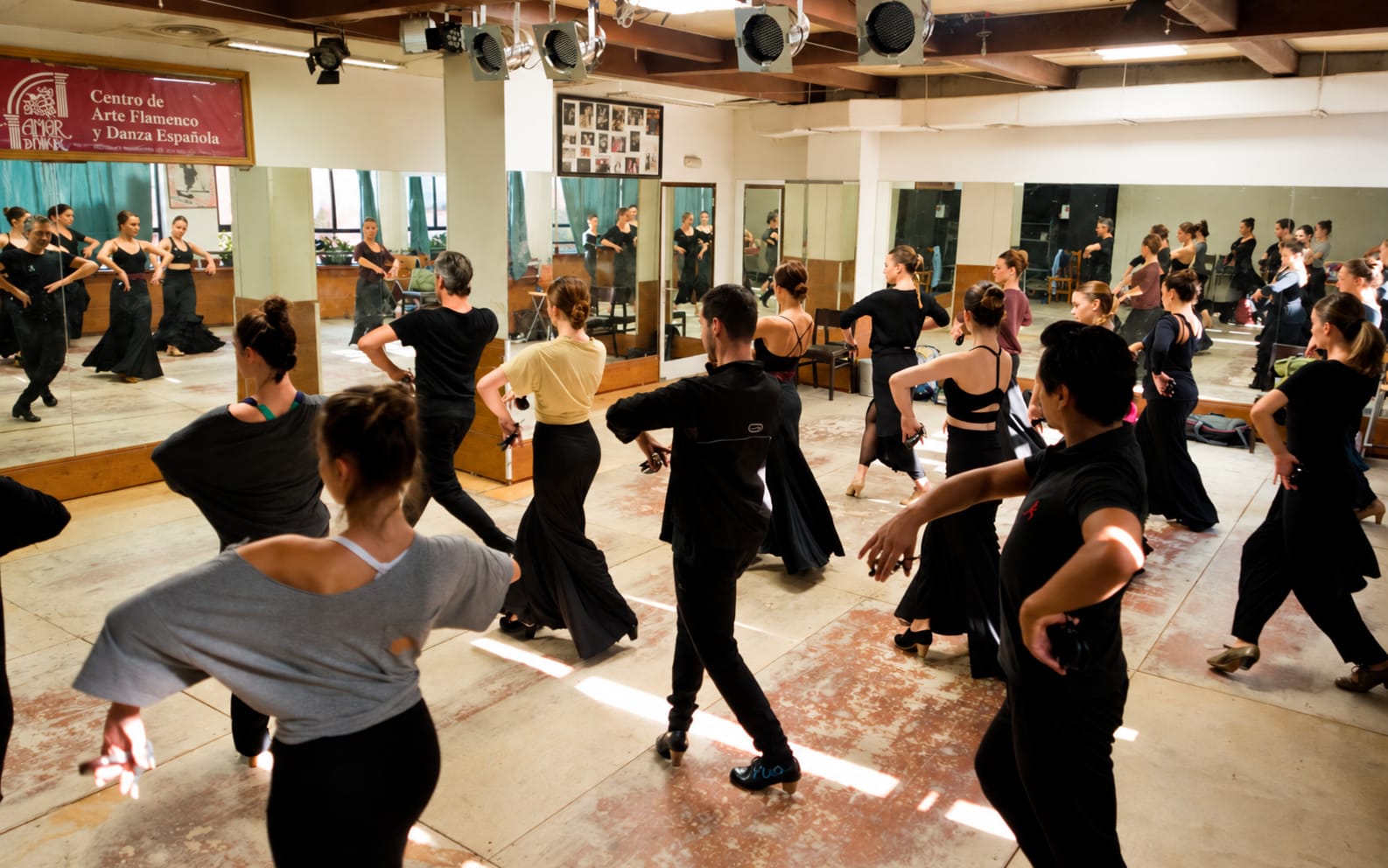 Grupo practicando movimientos flamencos en una sala de danza