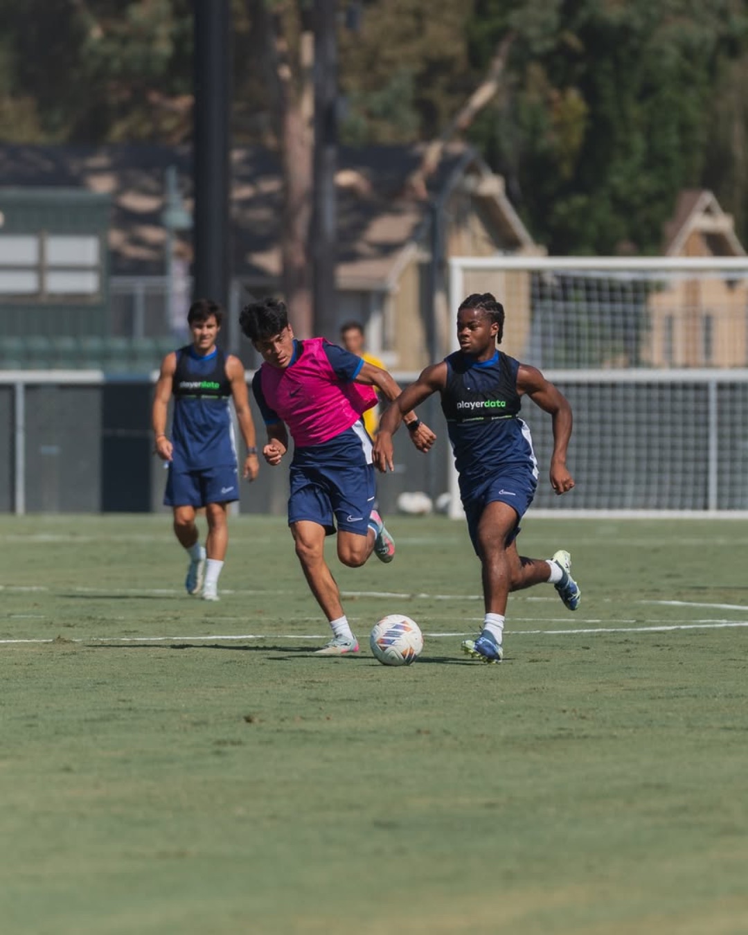 Players in PlayerData vests during a grassroots training match