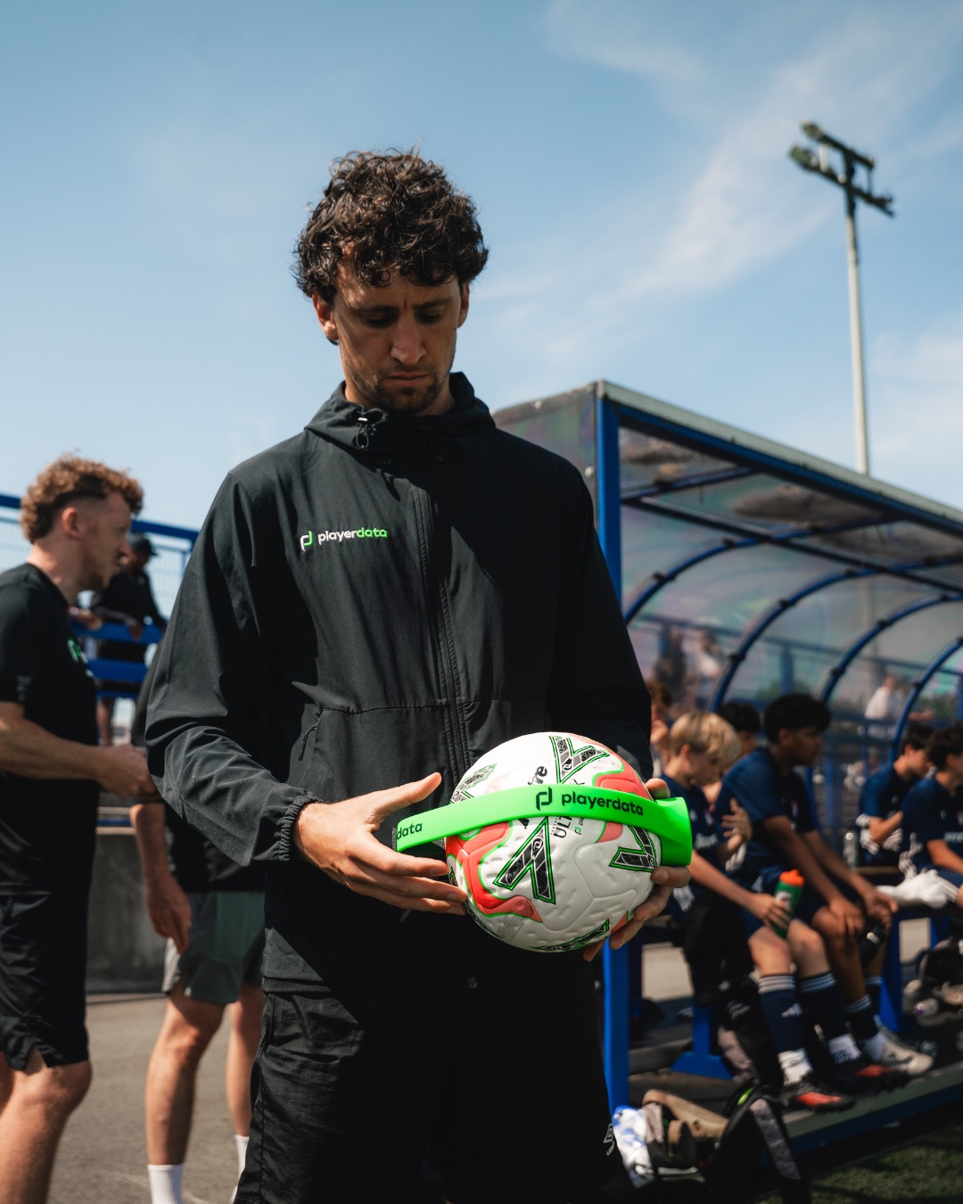 Coach holding a smartball with PlayerData sensor pitchside