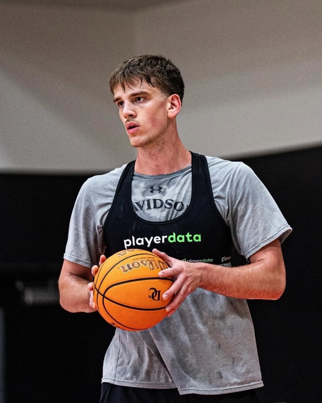 College basketball player in a PlayerData vest holding the ball