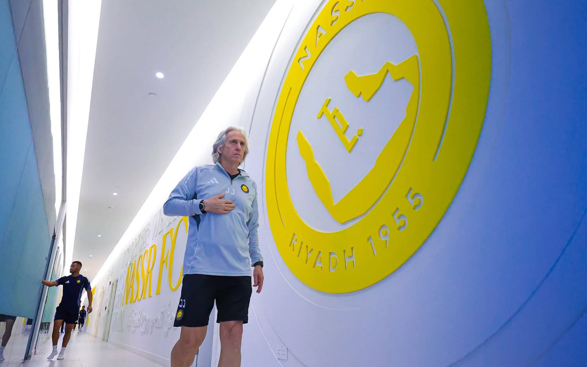Al Nassr — coach walking past the club crest wall