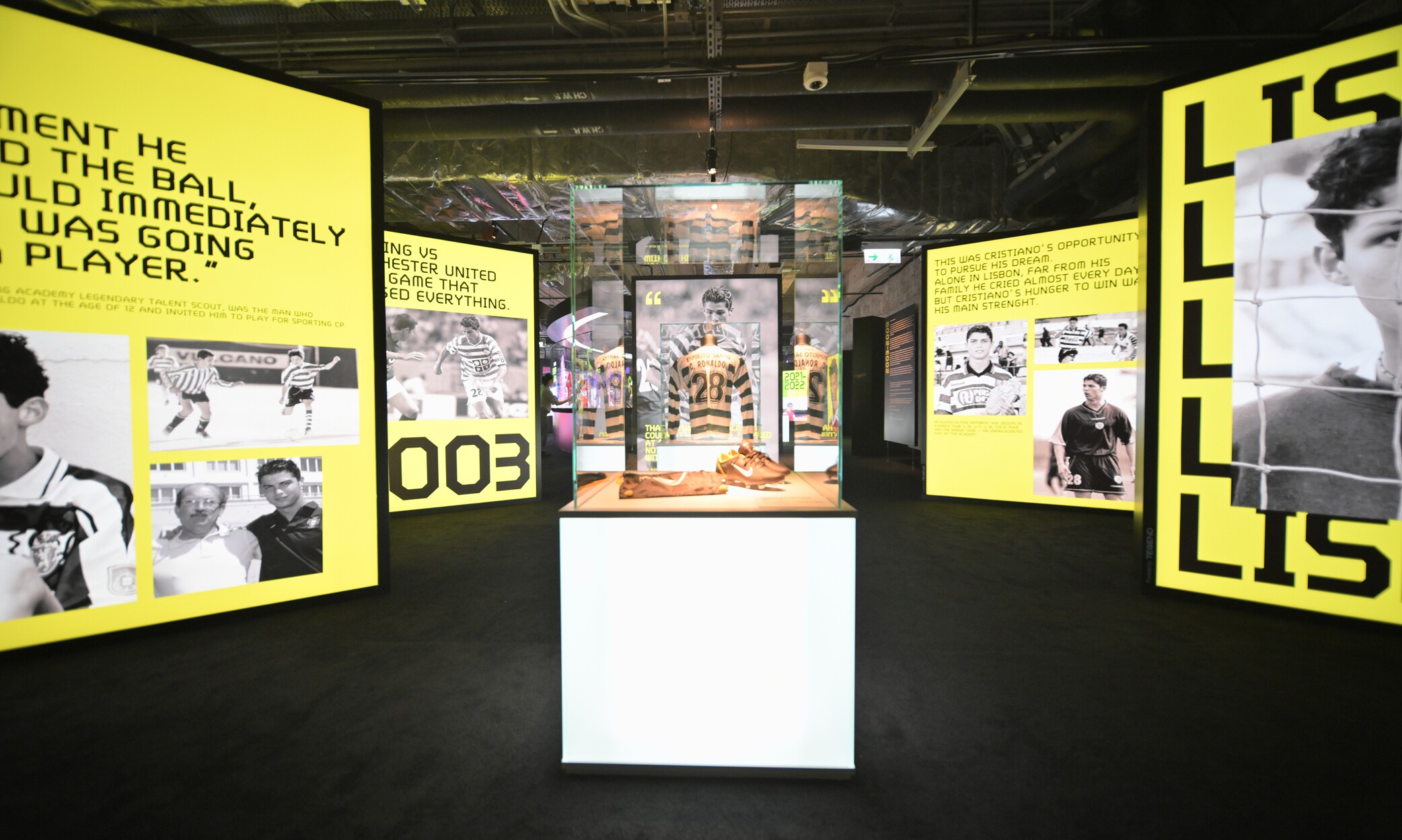 CR7 Life Museum — Lisbon gallery with yellow display panels and boots in a lit case