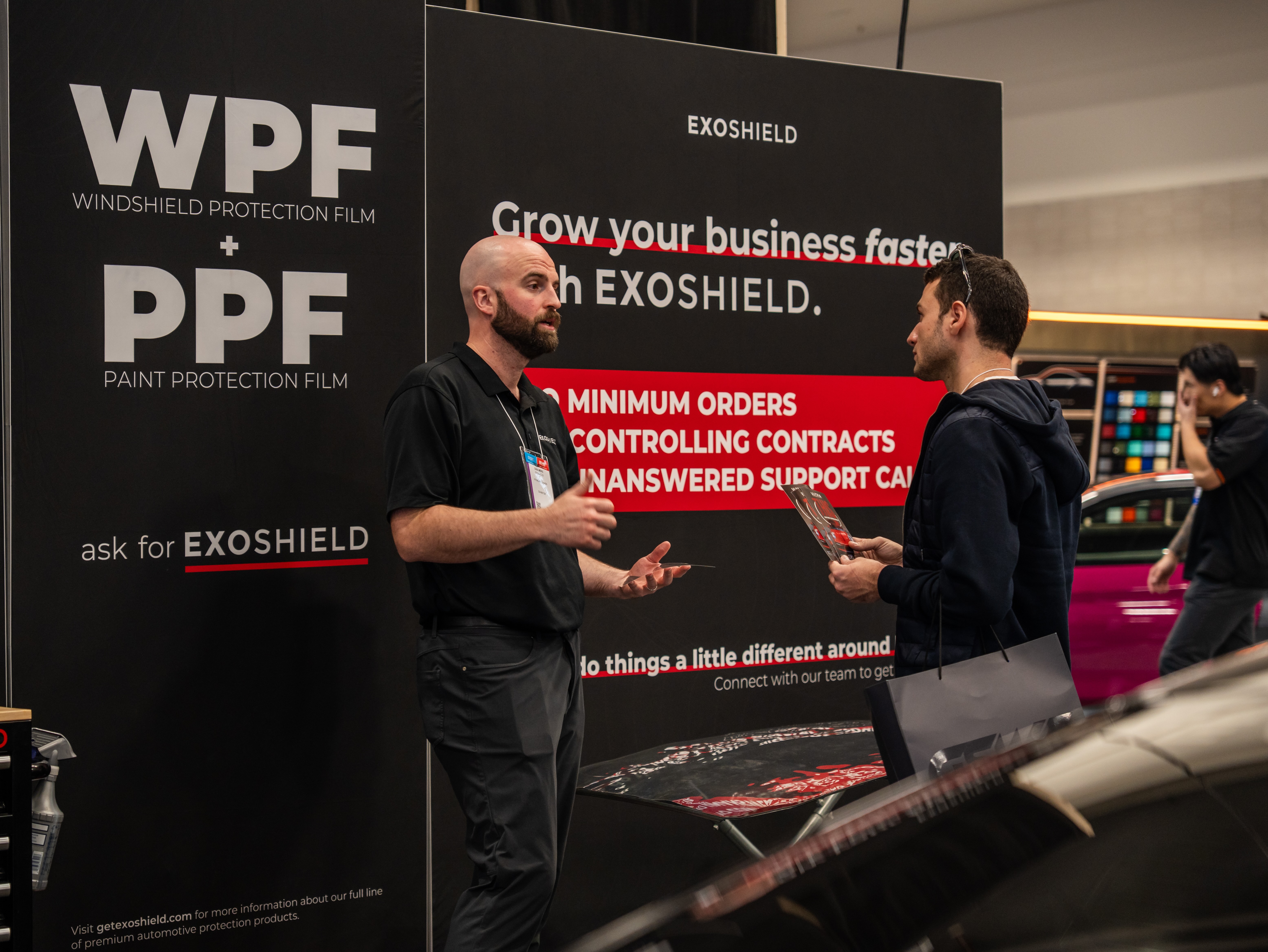 ExoShield employee demonstrating windshield protection film to a potential client at SEMA 2025