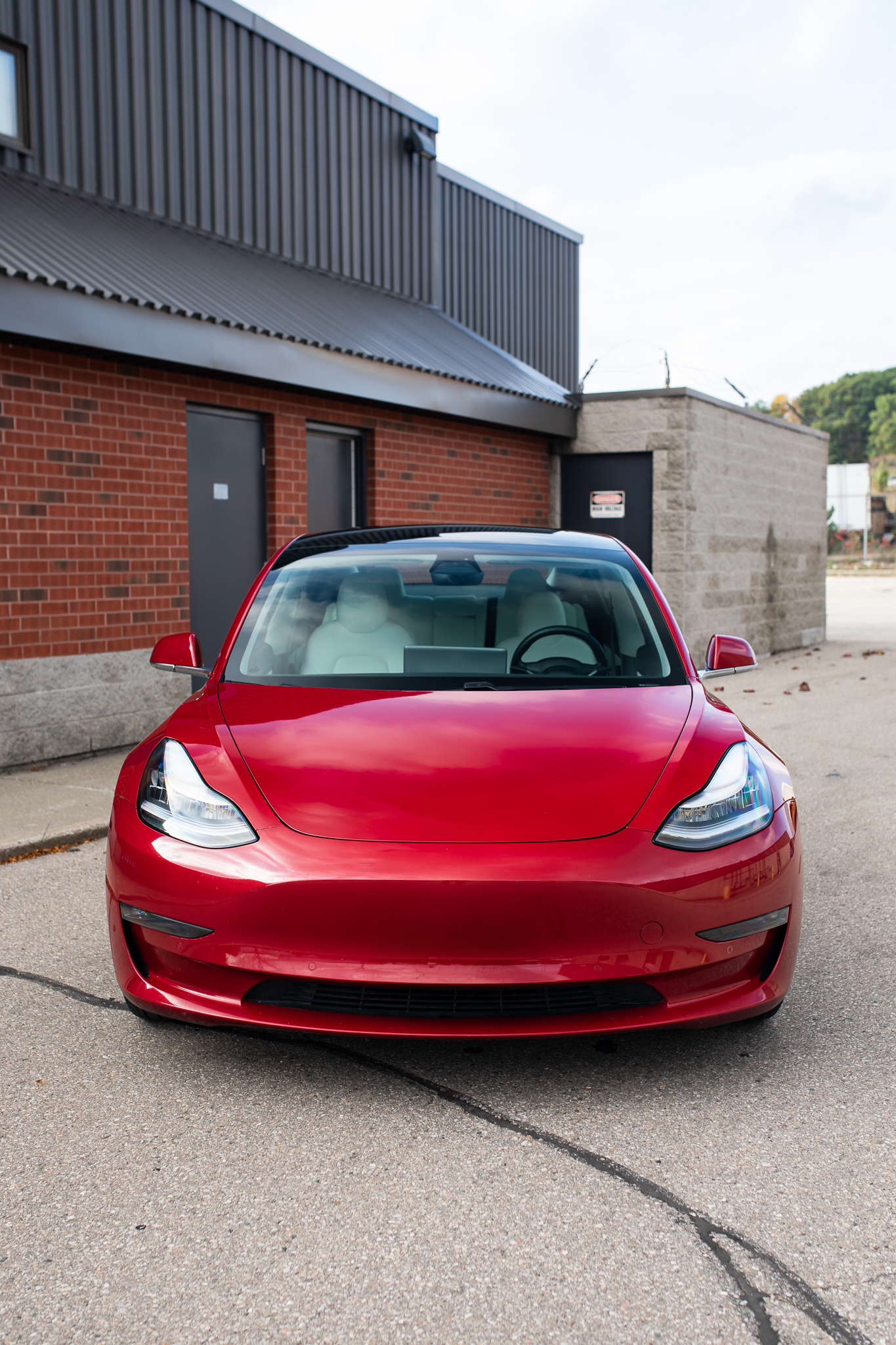 Head on Photograph of a red Tesla Model 3 showcasing the windshield head on.