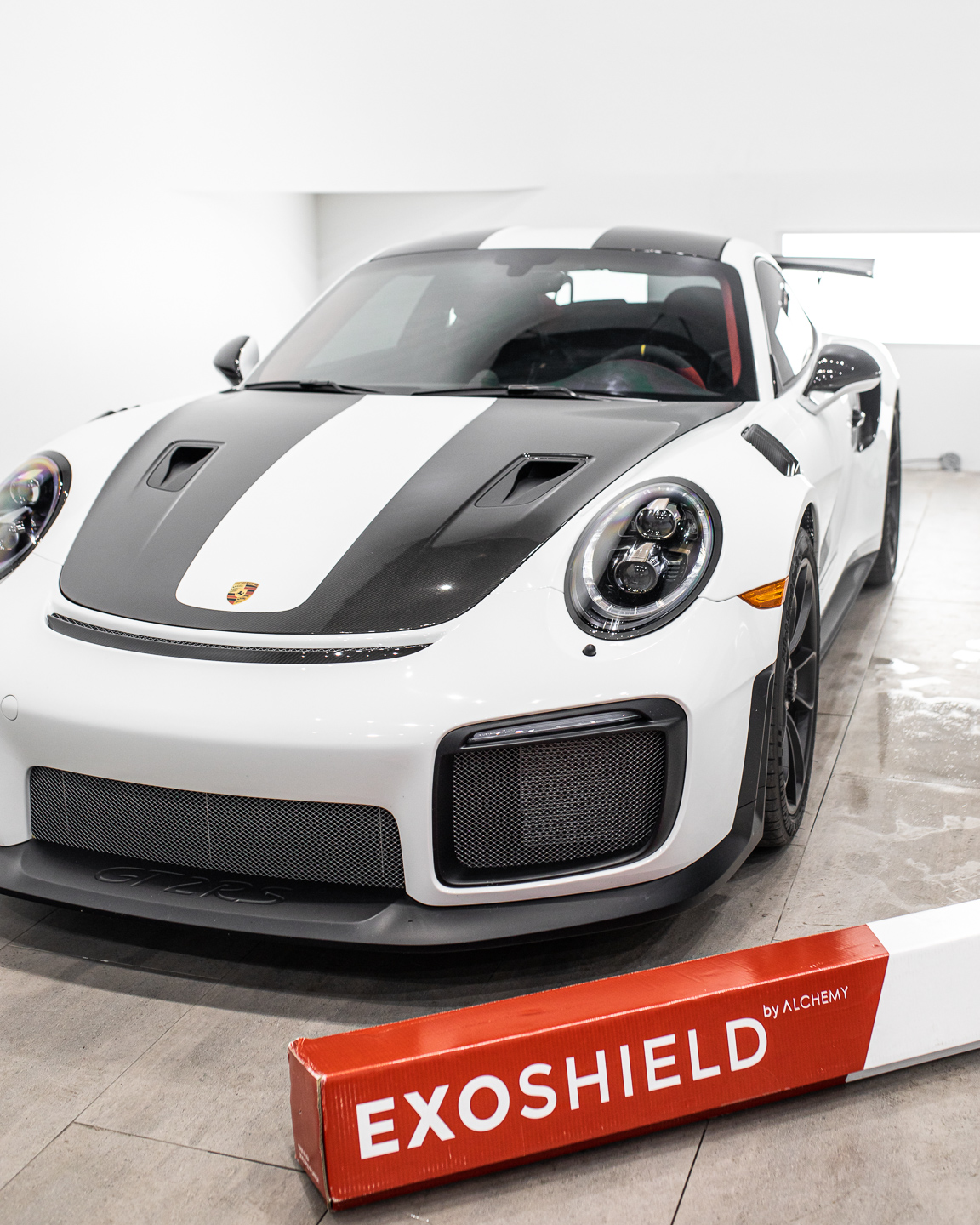 White Porsche GT3RS in a clean autoshop with ExoShield windshield protection film installed on the windshield.