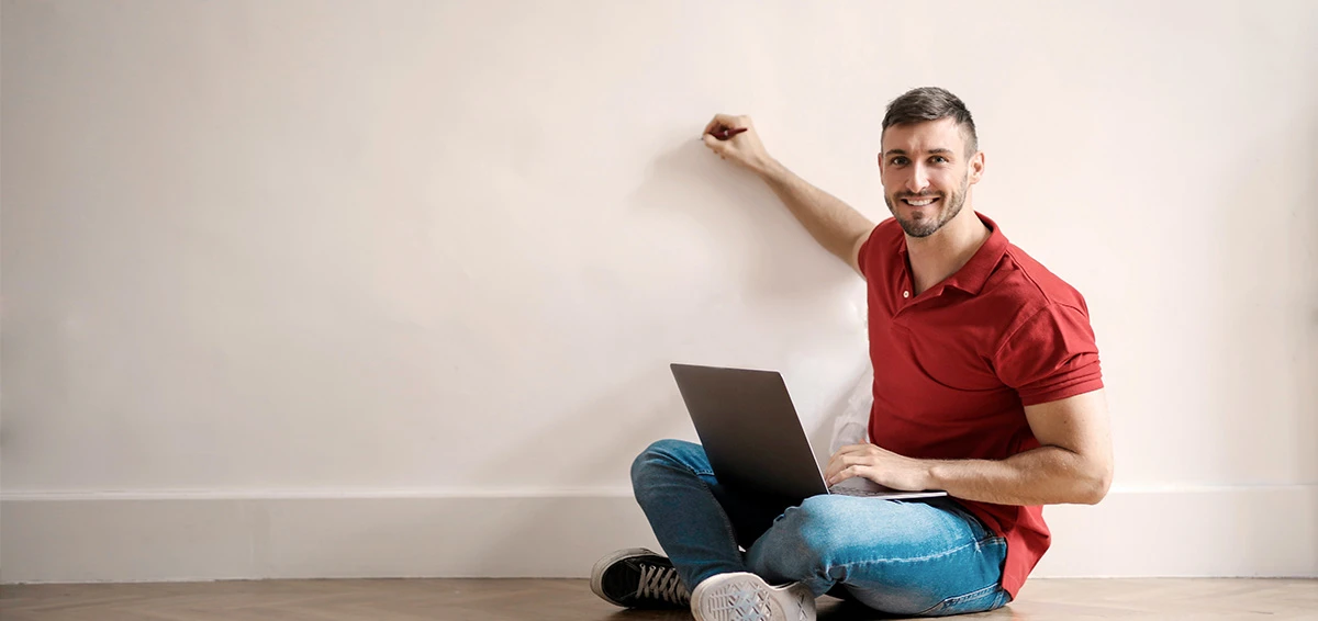 Man with his laptop pointing a pen in the wall