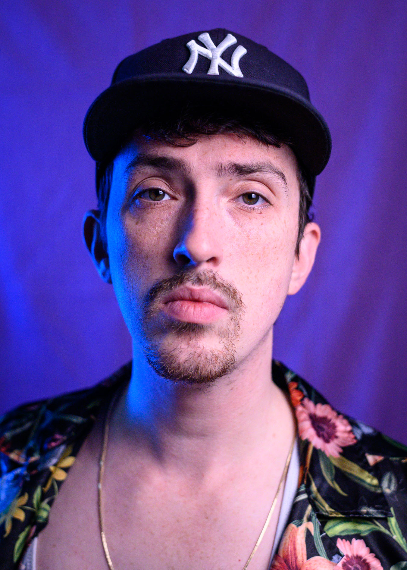a person with facial hair, a yankees cap and a floral shirt