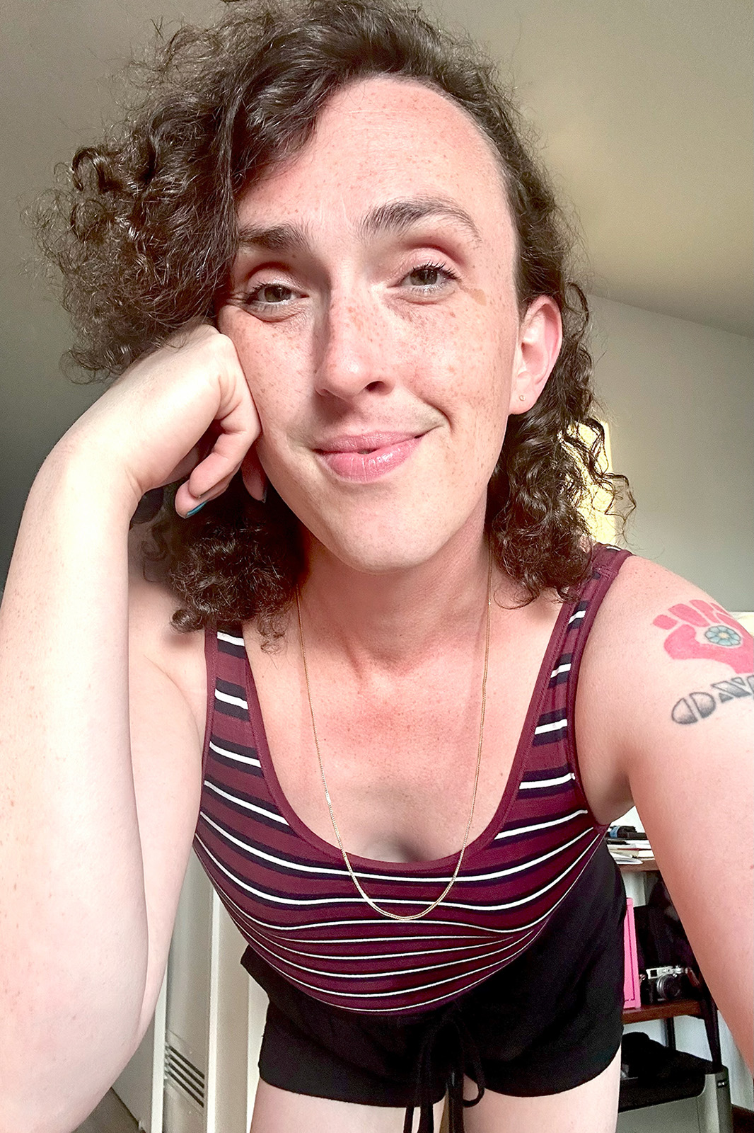 a recent selfie of the artist in a maroon top and gold chain