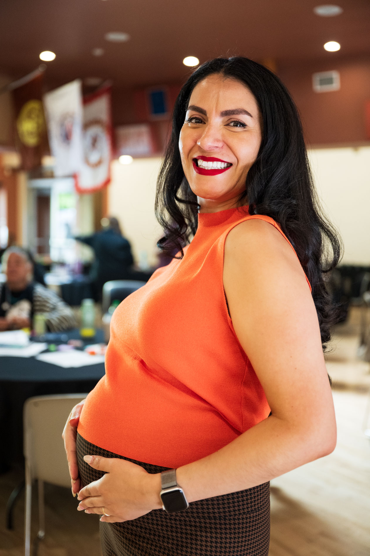 A smiling pregnant professional poses for a portrait at a community event. This is an example of an inclusive headshot for a nonprofit in Portland, Oregon.