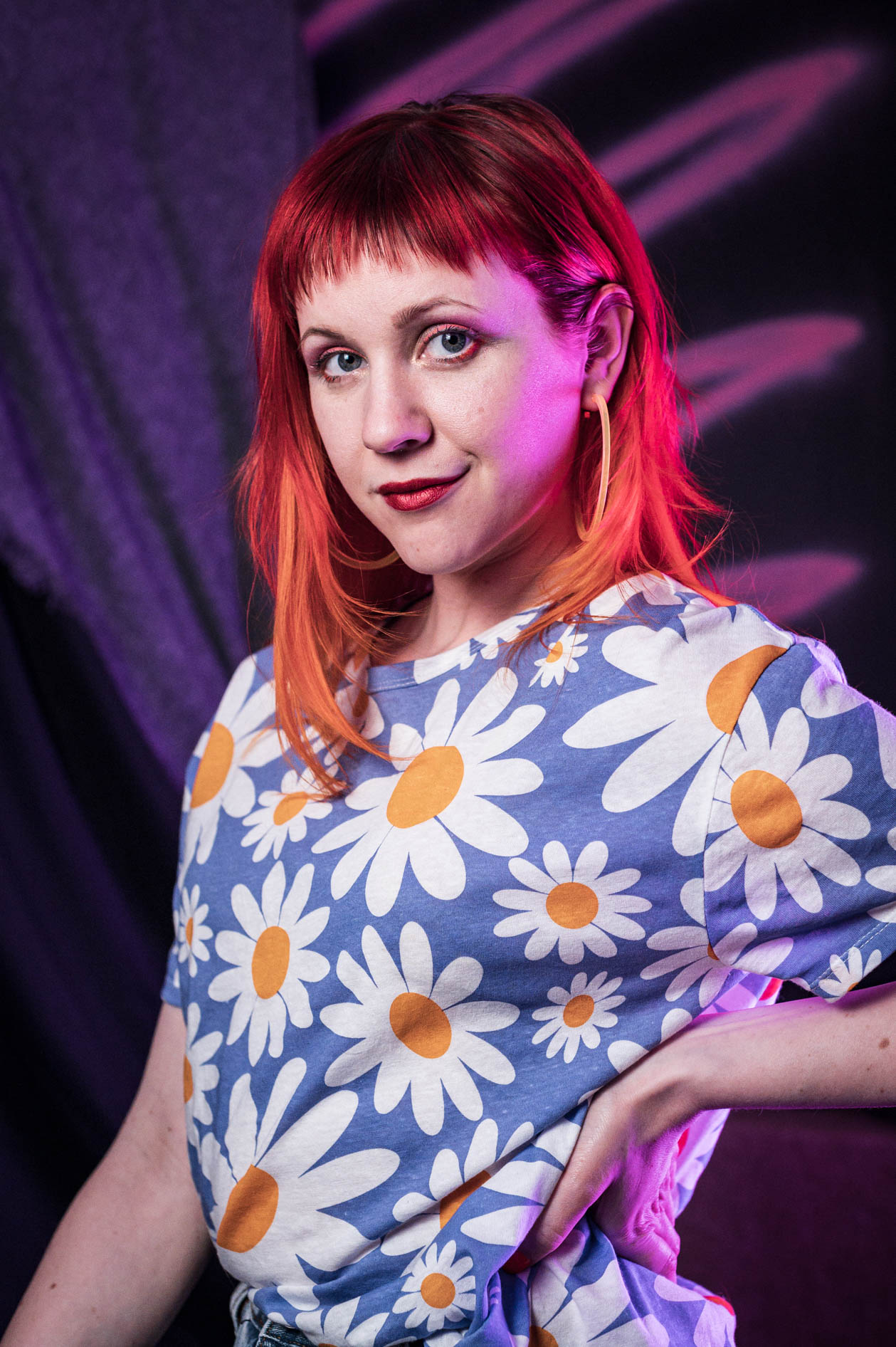 A smiling entrepreneur with red hair and a daisy-print shirt poses for a studio portrait in Portland, Oregon. This is an example of authentic portraits and brand storytelling.