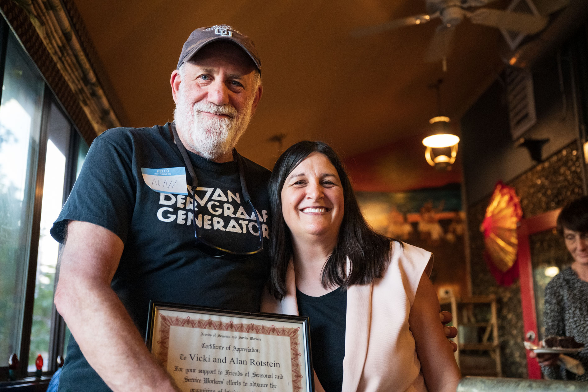 A smiling couple poses for a photo, holding a framed certificate of appreciation. This is an example of an event photographer capturing an achievement award ceremony in Portland, Oregon.
