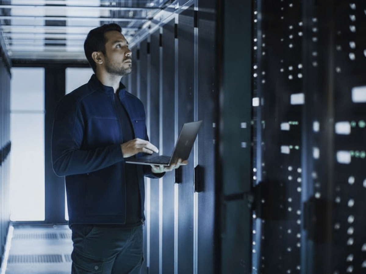 IT consultant working on a laptop inside a data center surrounded by servers, representing fractional CIO services focused on technology strategy, infrastructure management, and digital transformation